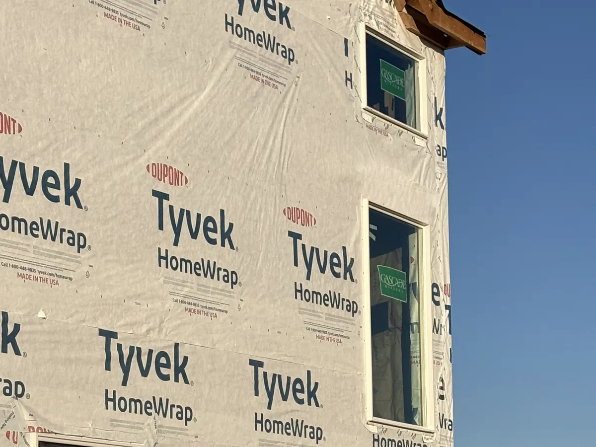 Two-story home fully wrapped in Tyvek HomeWrap with windows installed and flashed, framed by JJC Construction