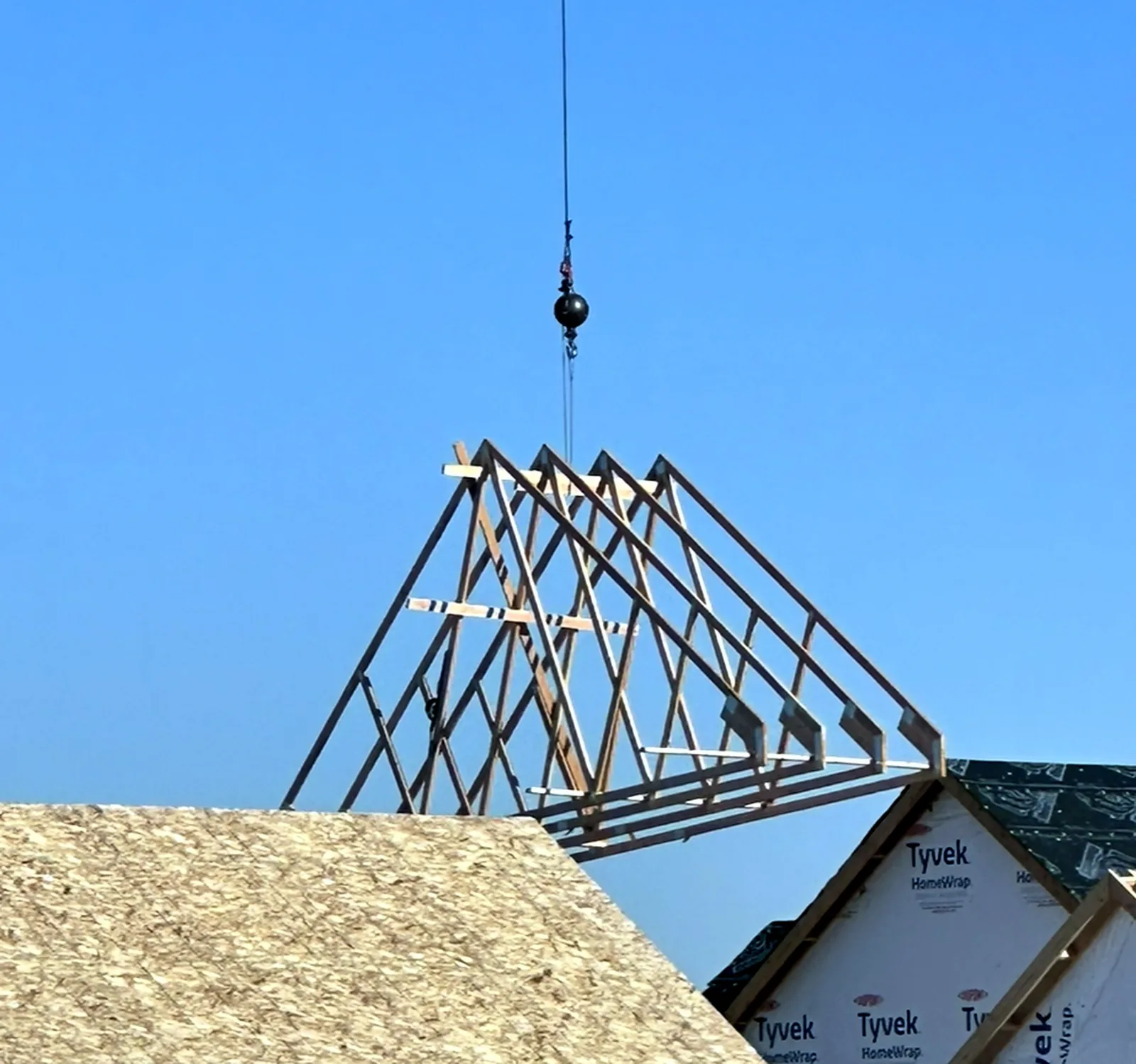 A crane lifting a bundle of roof trusses into place